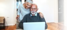 A senior couple working on a laptop and checking their finances.